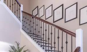 Curved staircase with black railing and framed wall art